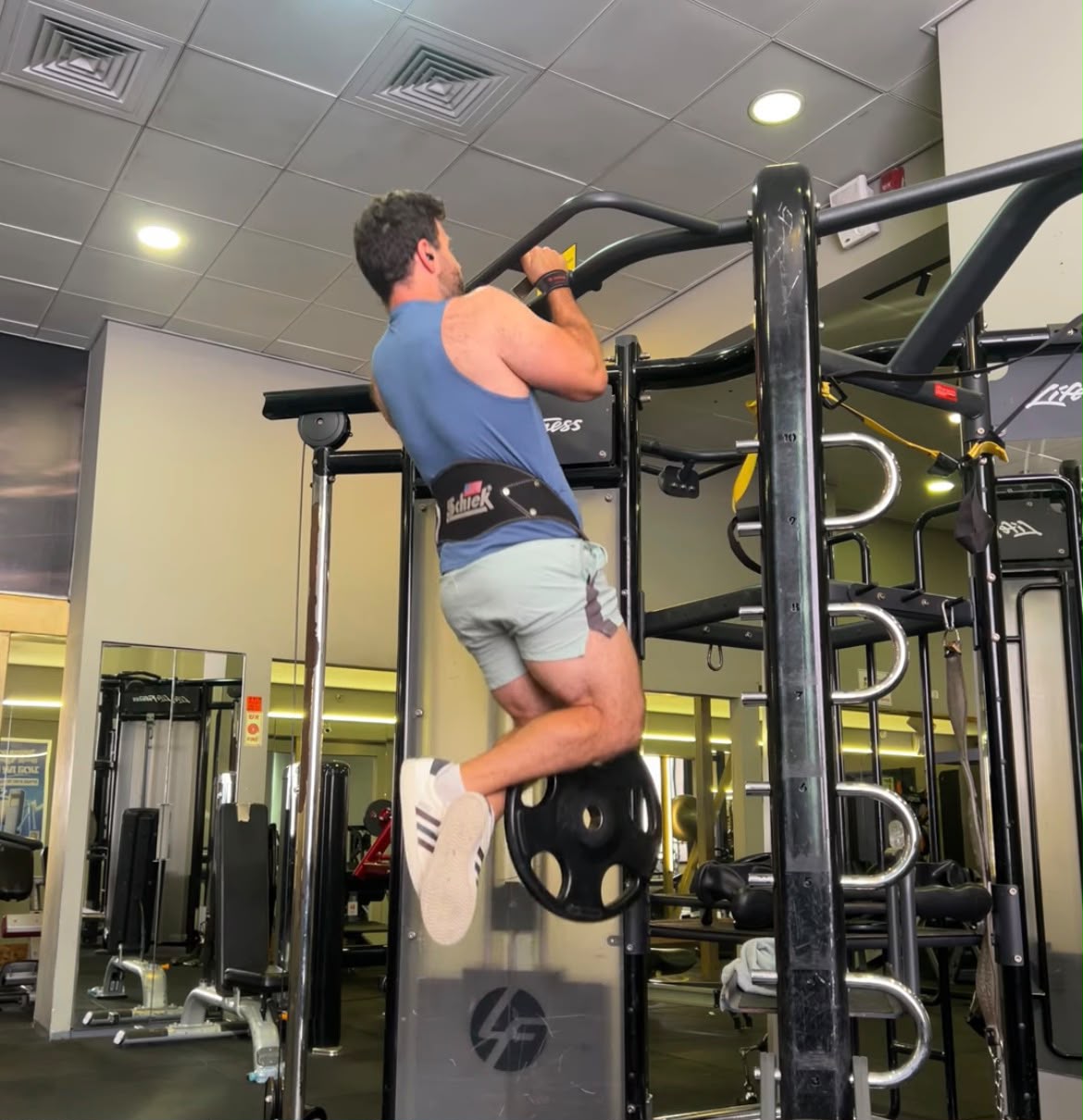 Adam Grossman doing a weighted pull-up on a gym rig