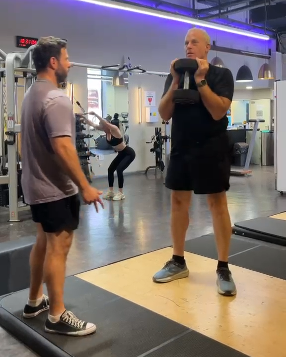 Adam Grossman coaching an older client through a dumbbell lift